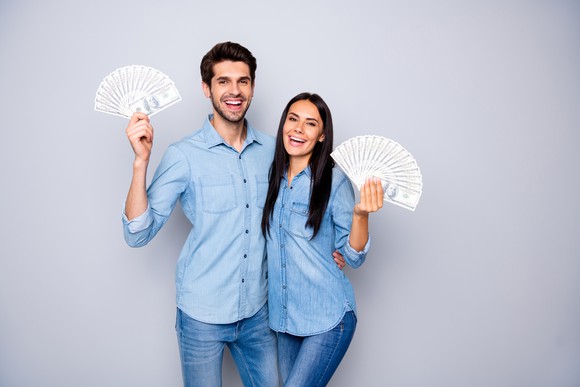 Smiling young man and woman holding cash in their hands
