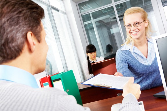 Woman handing form to financial advisor.