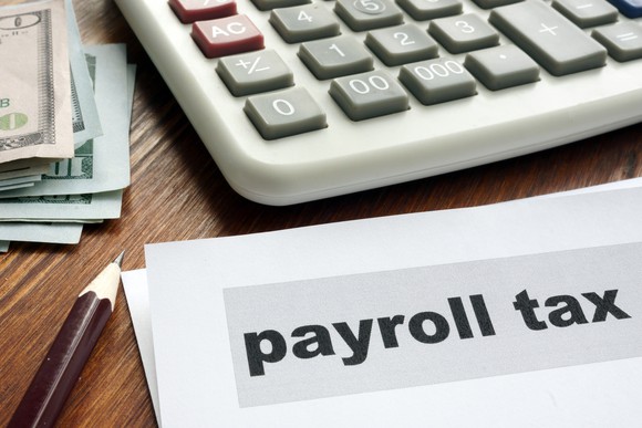 Payroll tax papers, calculator and money.