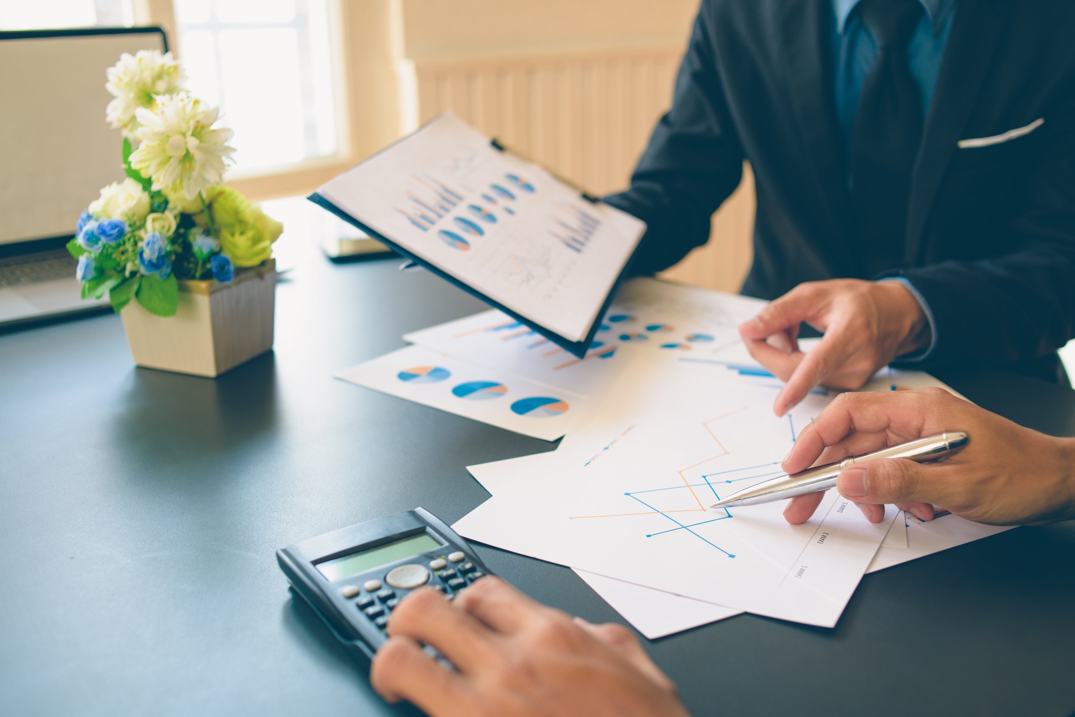 Two people looking at charts and one is using a calculator.