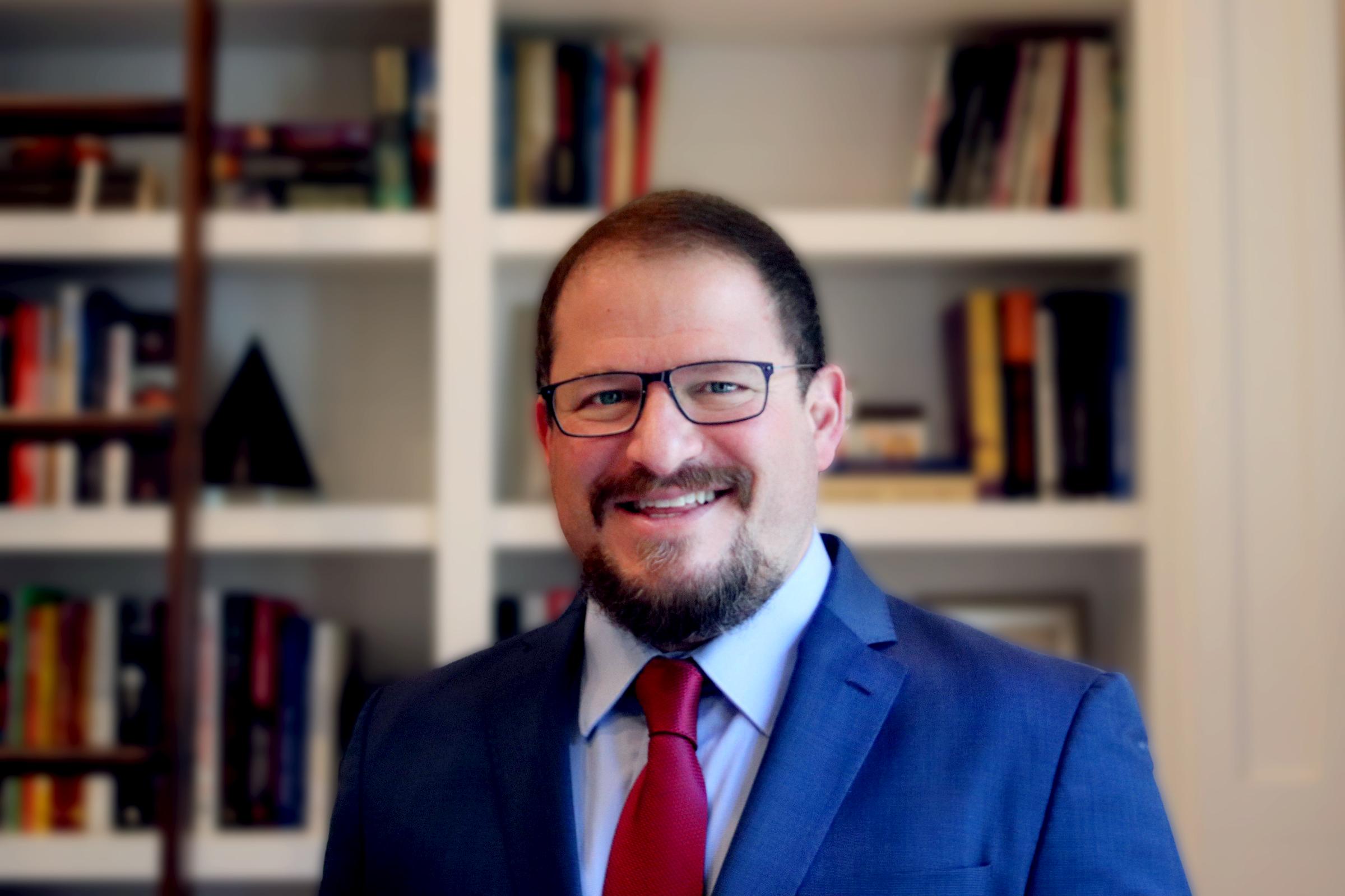 A photo of incoming Qualcomm CEO Cristiano Amon, smiling in front of a bookcase.
