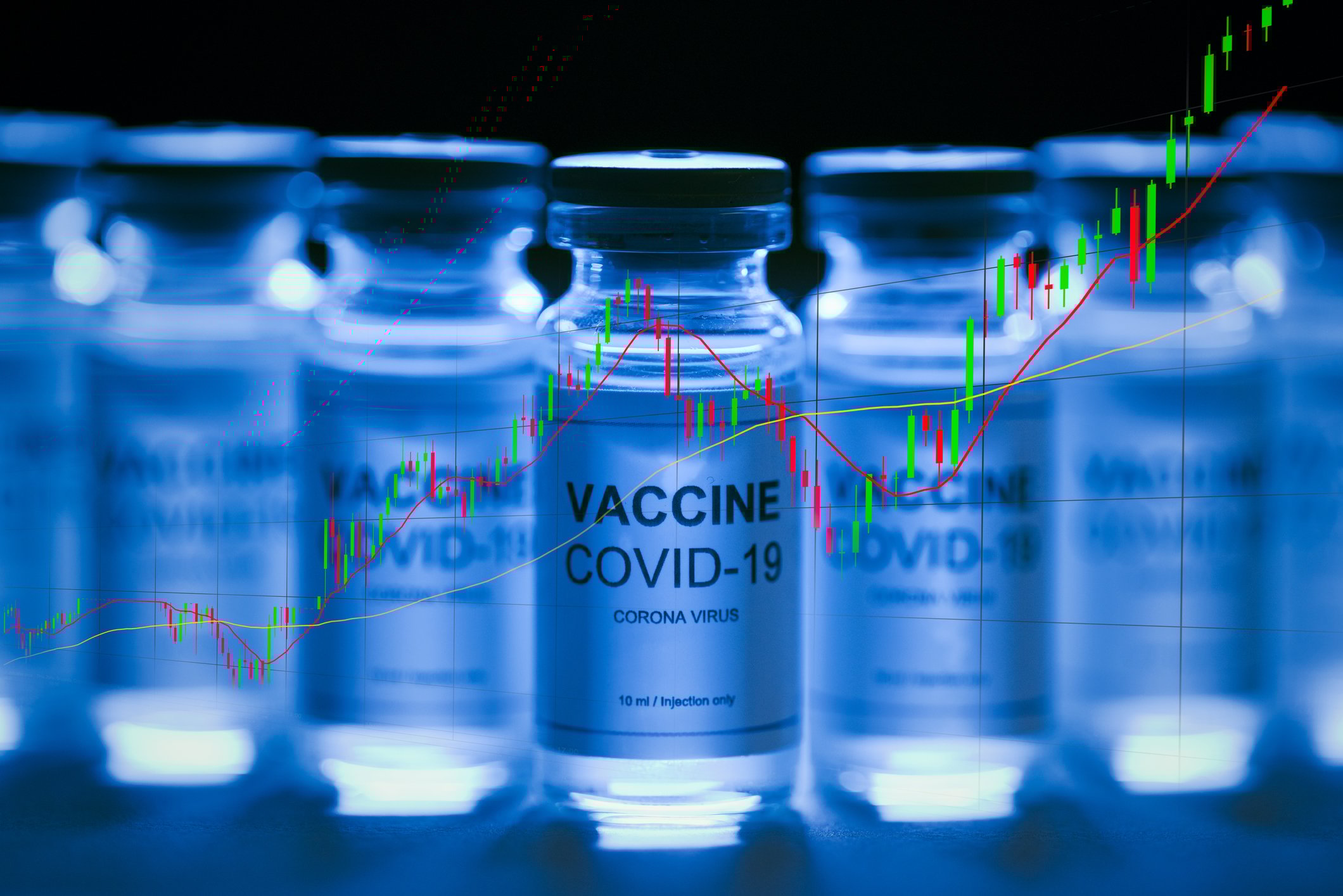 A table of COVID-19 vaccine vials with an ascending trend line superimposed over the vials.