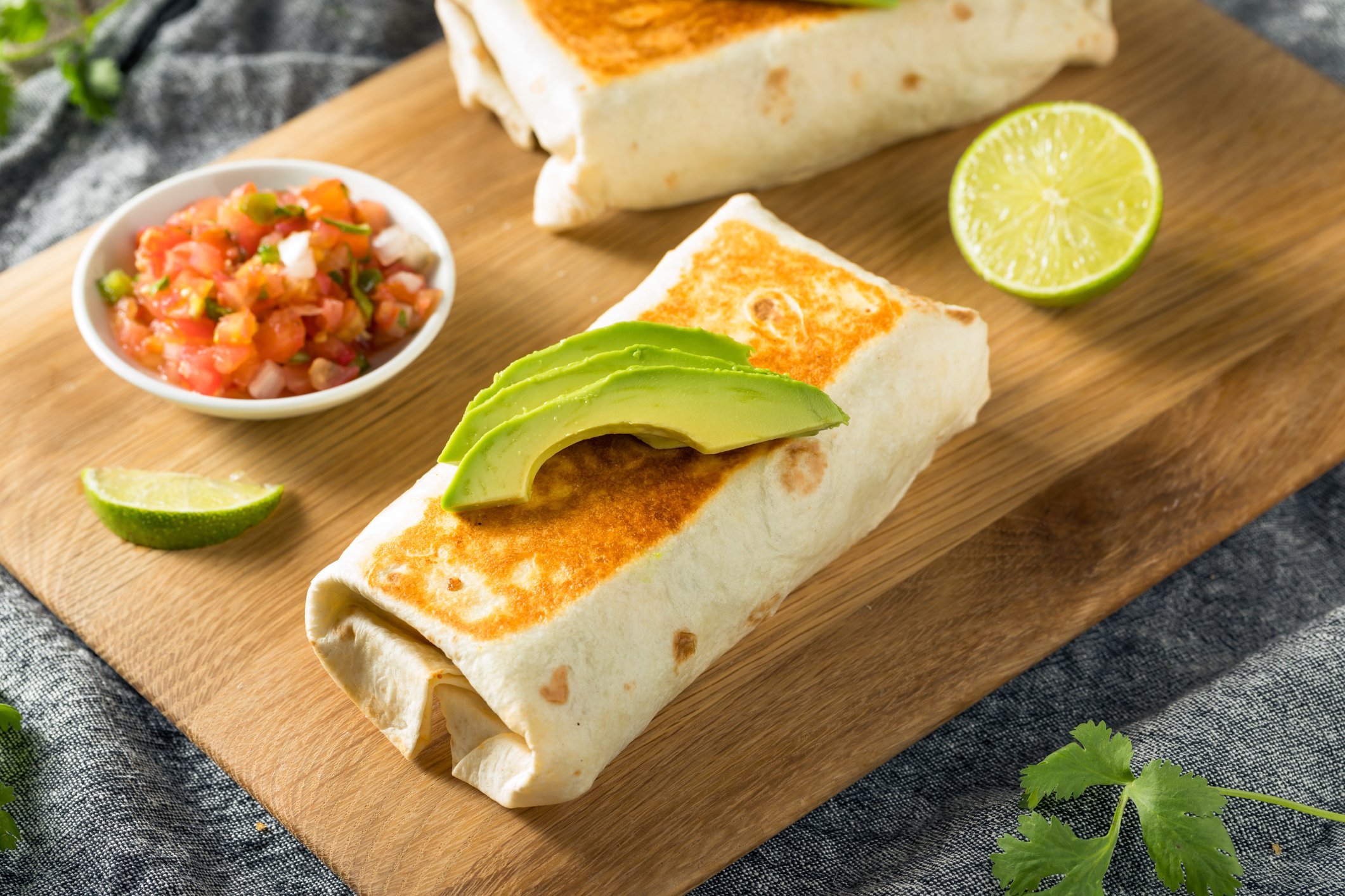 A burrito topped with avocados. 
