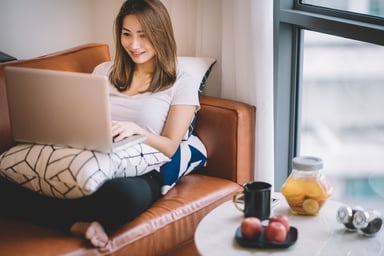 a woman sitting on a sofa using a laptop