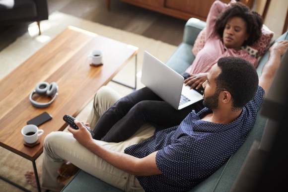 A couple relaxes on the couch watching television