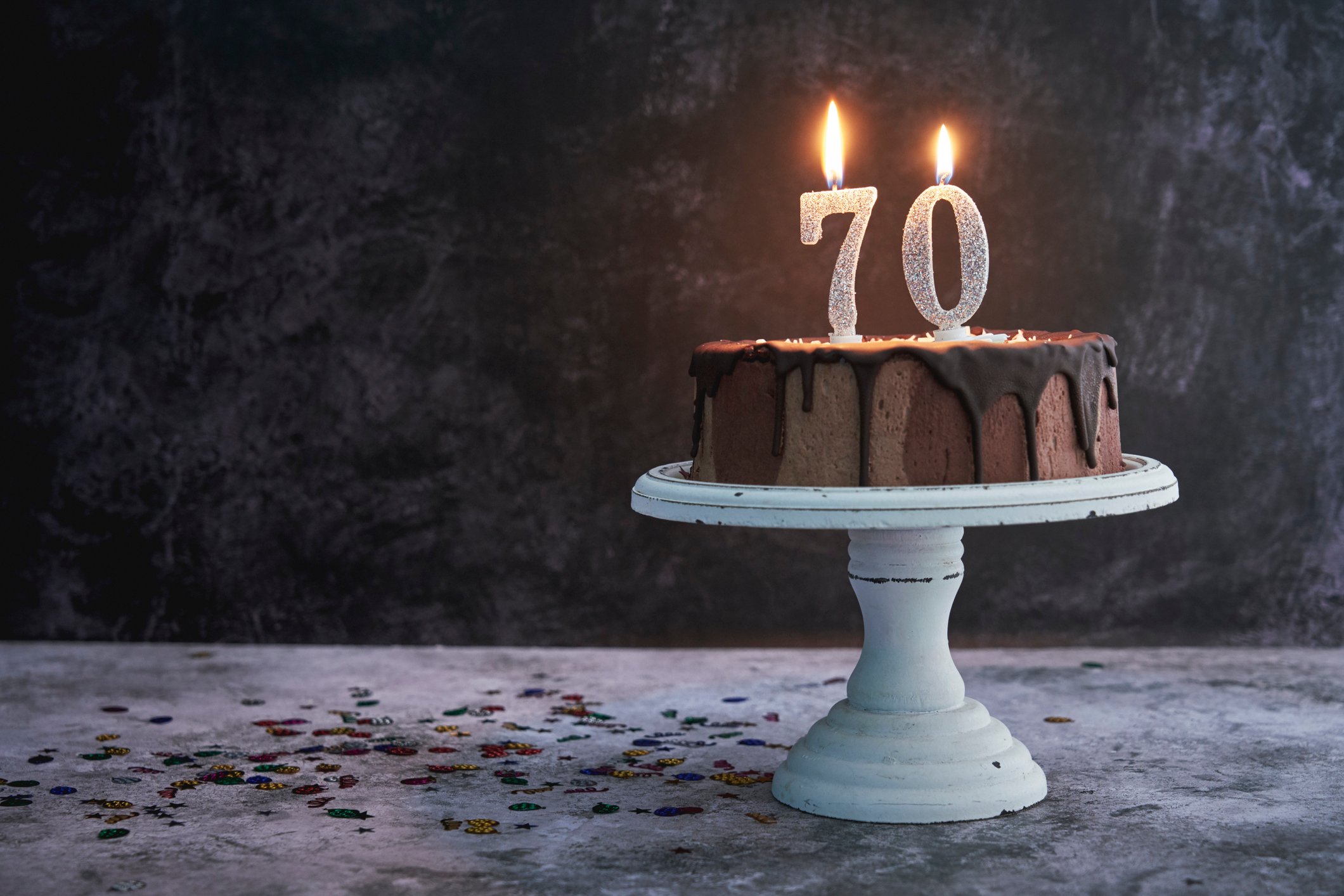 Chocolate cake with candles in the shape of 70 lit on top of it