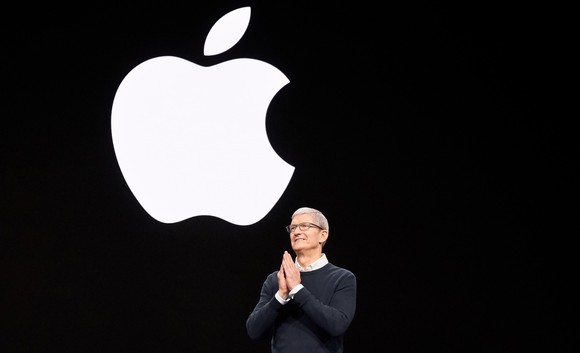 Tim Cook presenting onstage with large Apple logo behind him