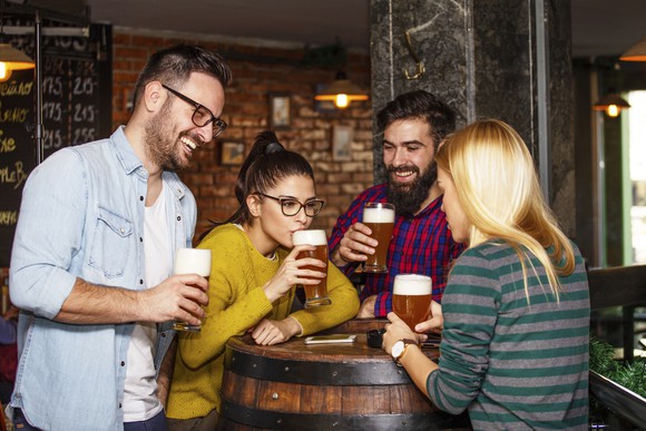 Friends drinking beer over a barrel