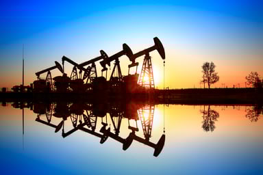 A row of oil pumps reflecting on the water.