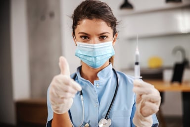 Nurse with vaccine syringe and thumbs up