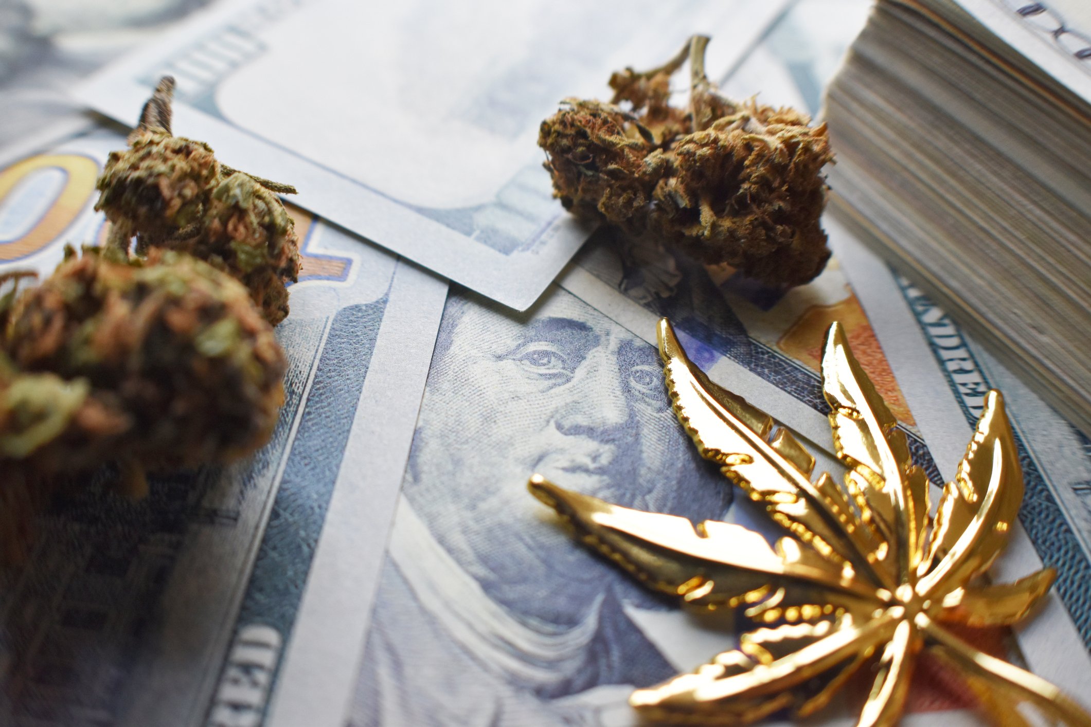Gold cannabis leaf, cannabis buds, and cash