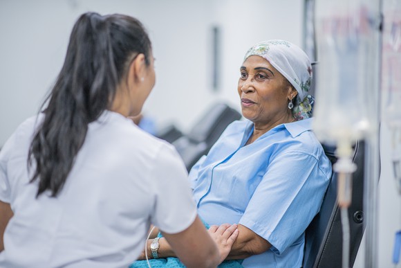 A cancer patient receiving an infusion with a nurse sitting beside her.