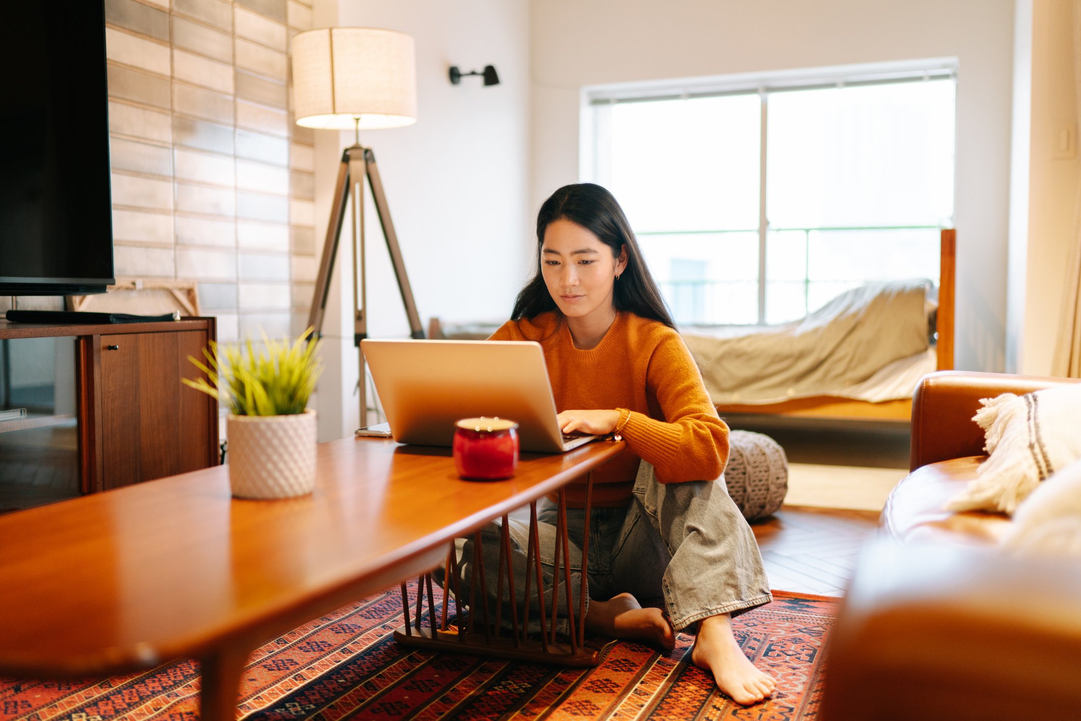 A young woman using a laptop at home.
