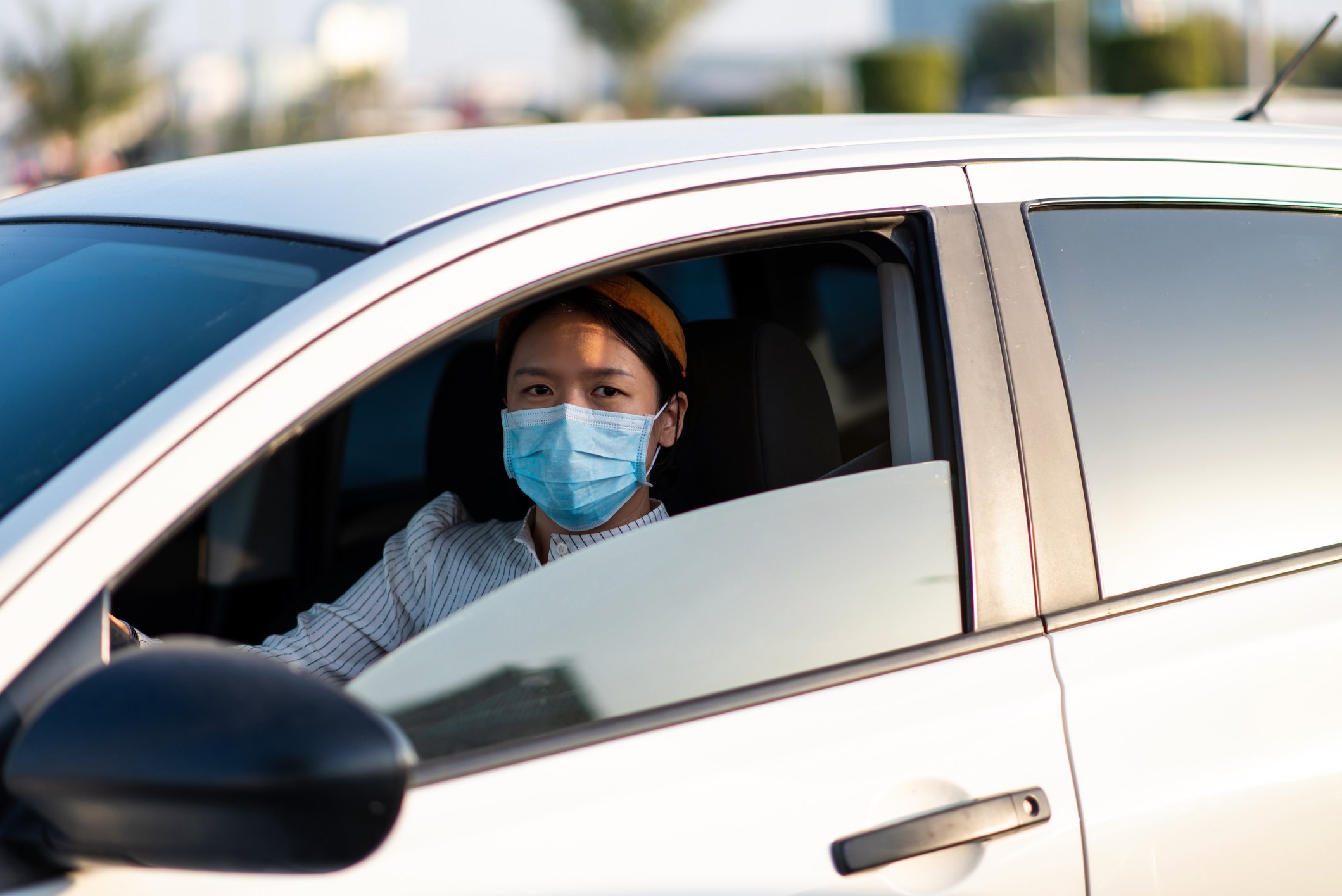 Woman in face mask driving a car.