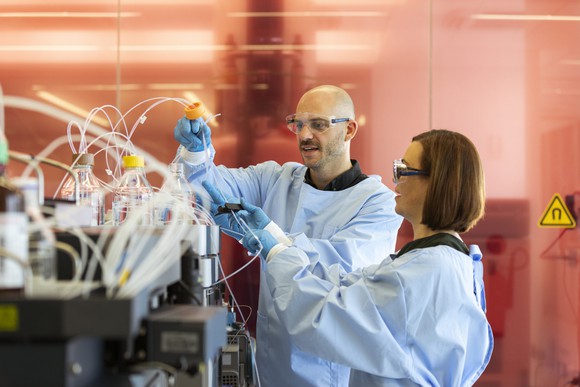 Two scientists operate a laboratory machine.