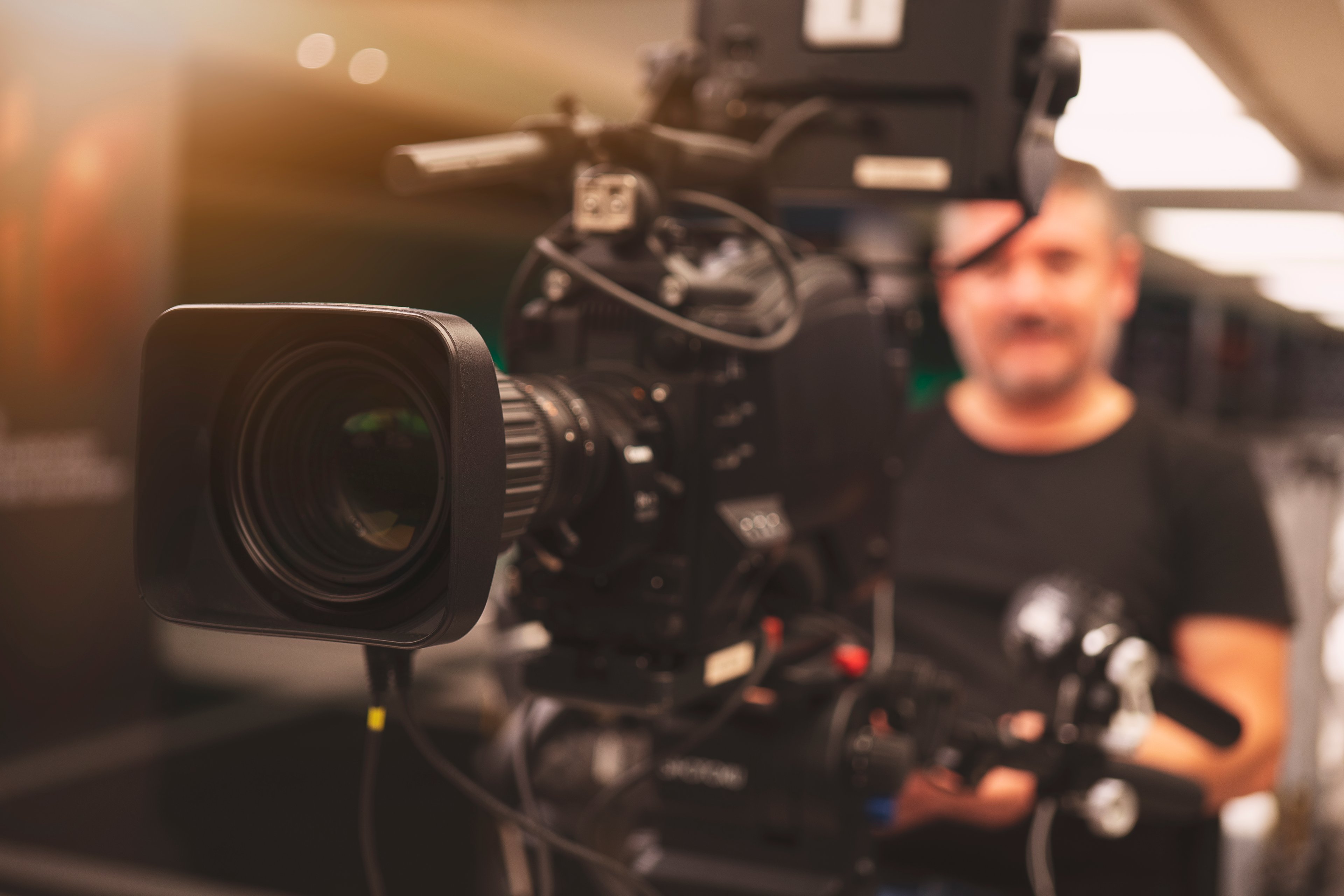 A cameraman sitting behind a movie production camera.