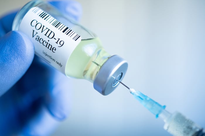 A researcher's hand draws a dose of coronavirus vaccine.