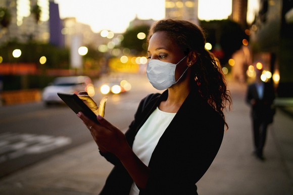 A woman wearing a mask and holding a mobile phone.