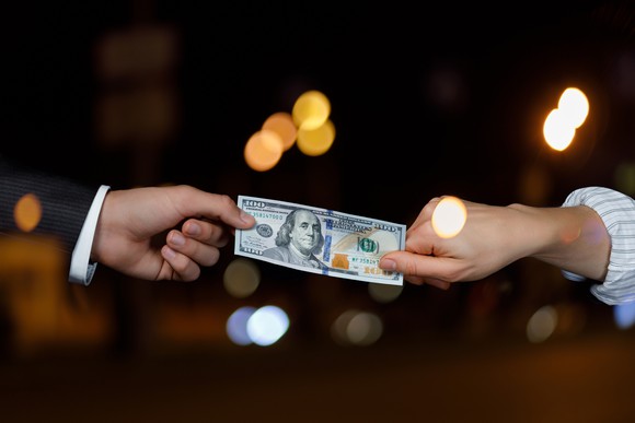 The hands of two people exchanging a bill.