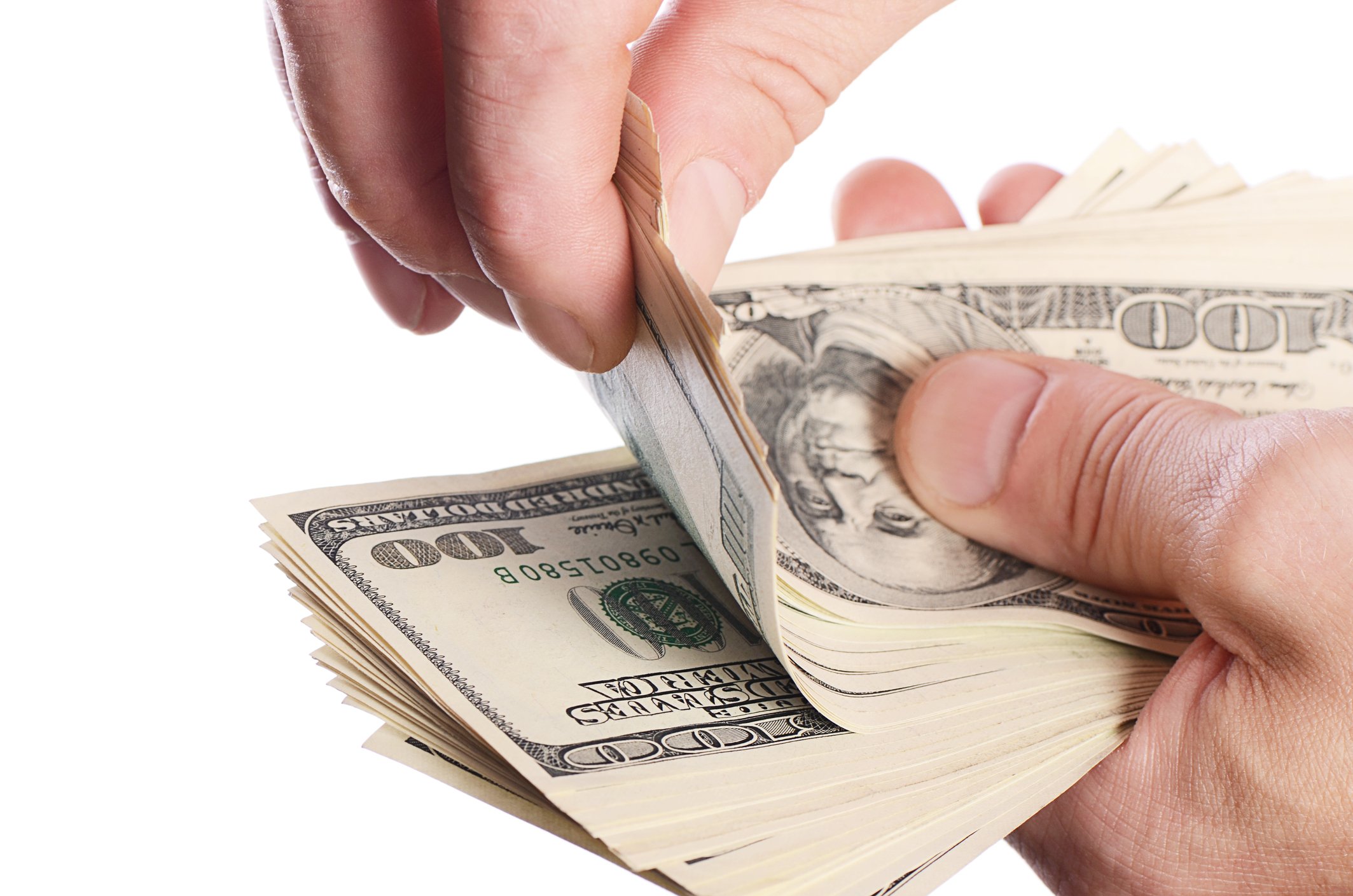A man takes a few hundred-dollar bills off the top of a much larger stack.