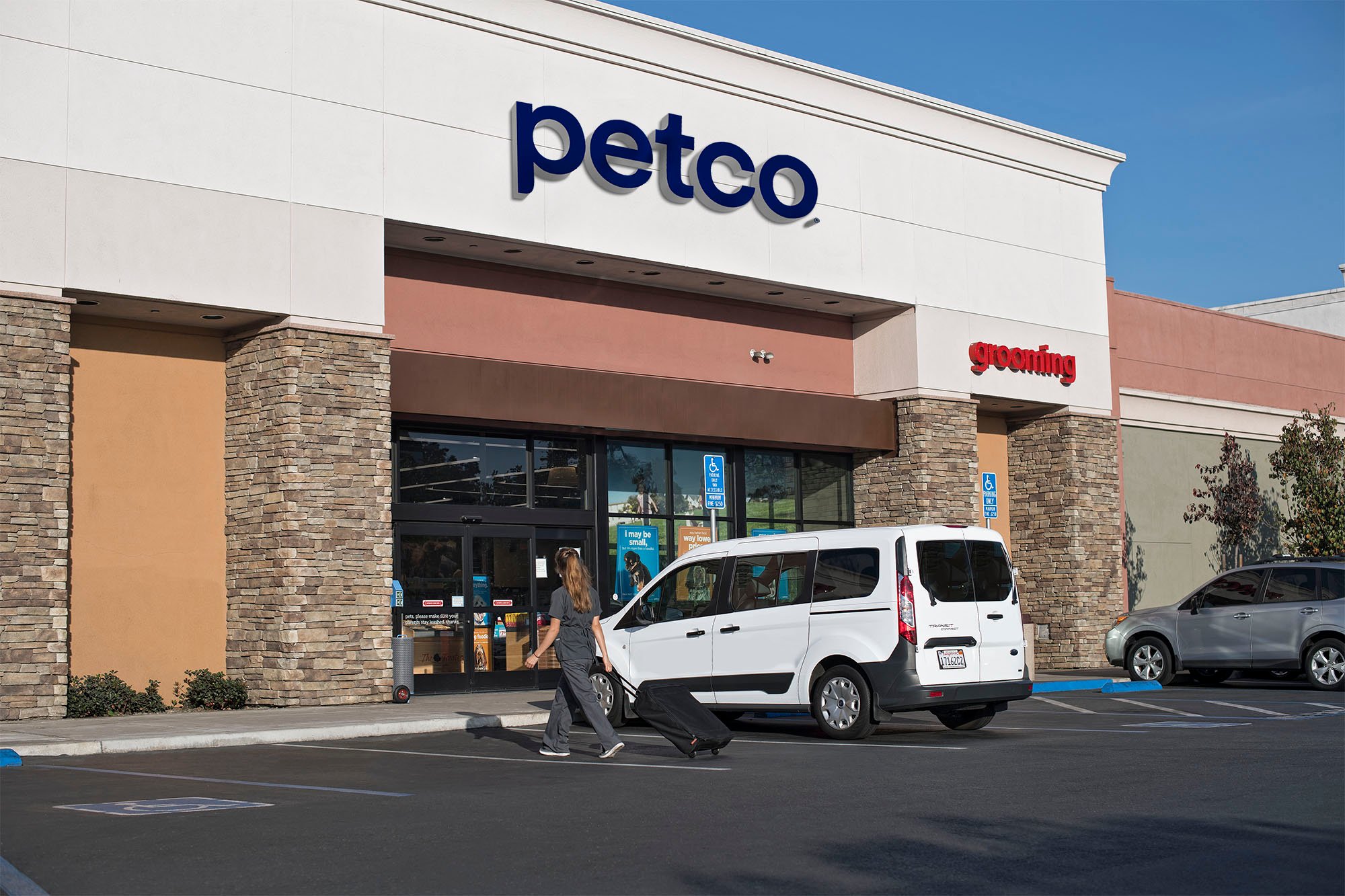 A Petco storefront with a minivan parked out front.