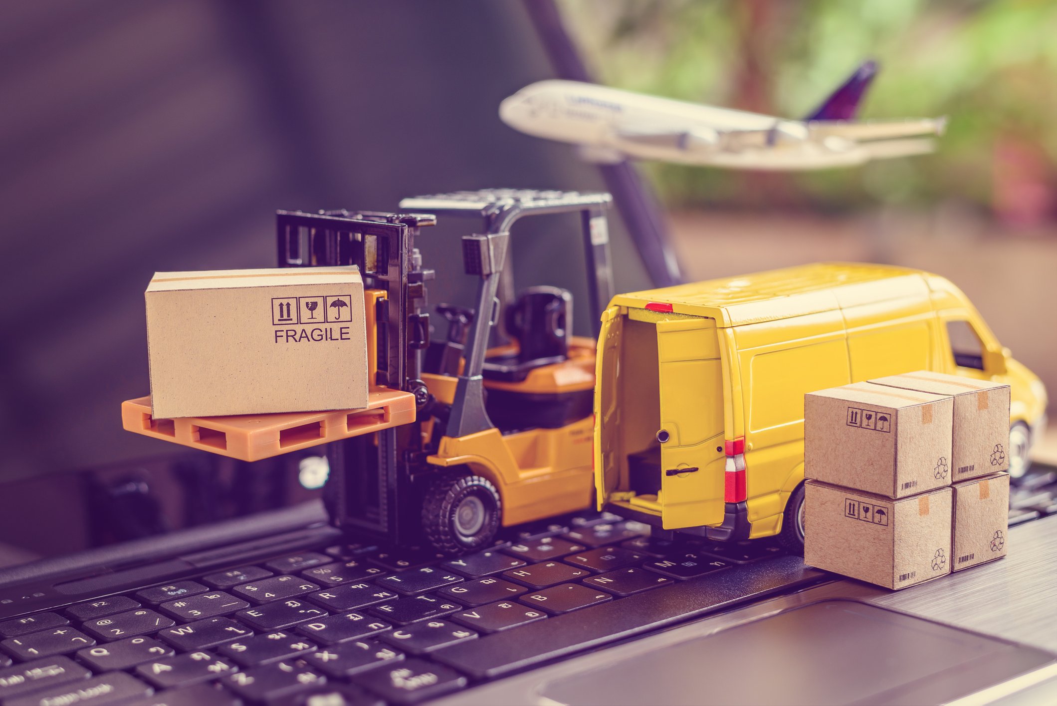 A model plane, forklift, and cargo van on top of an open laptop computer.
