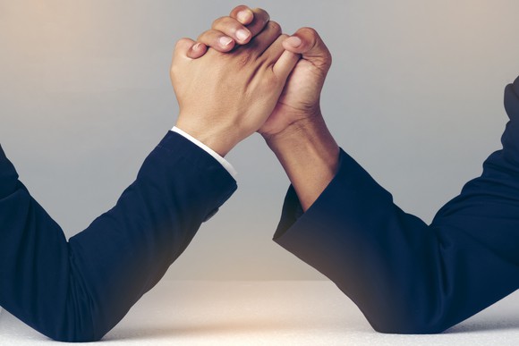 Two people in suits armwrestling