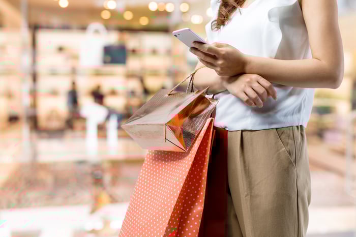 A woman checks her phone while shopping.