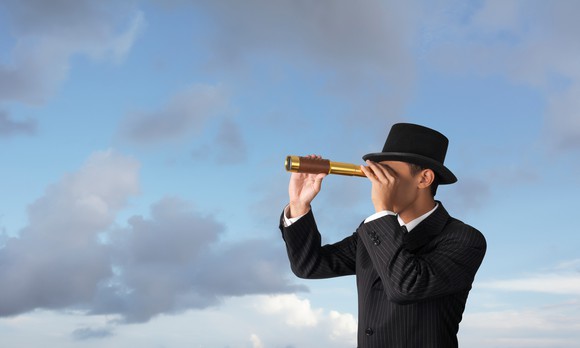 A businessperson looking through a telescope.