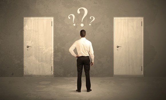 Man standing in front of two doors with question marks hovering above his head