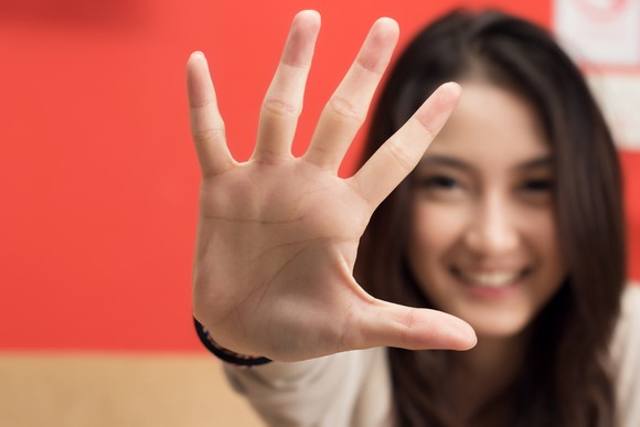 A woman smiling sticking out her right hand with all five fingers splayed