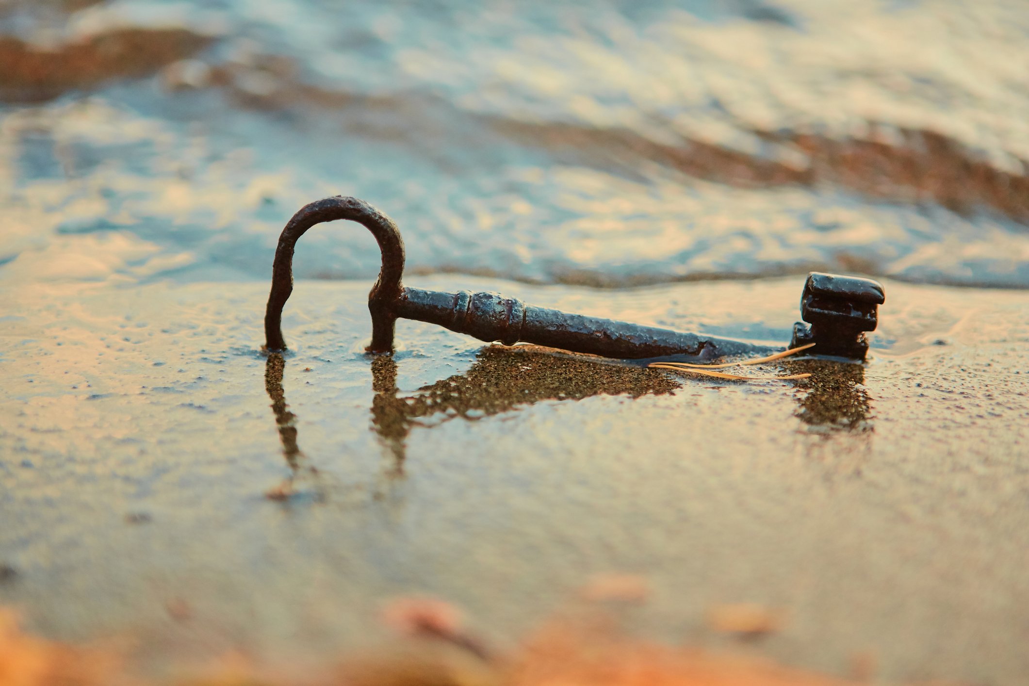 Rusty key in wet beach sand