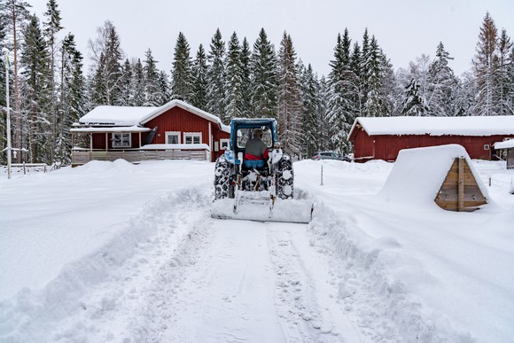 A tractor clears snow on a farm.