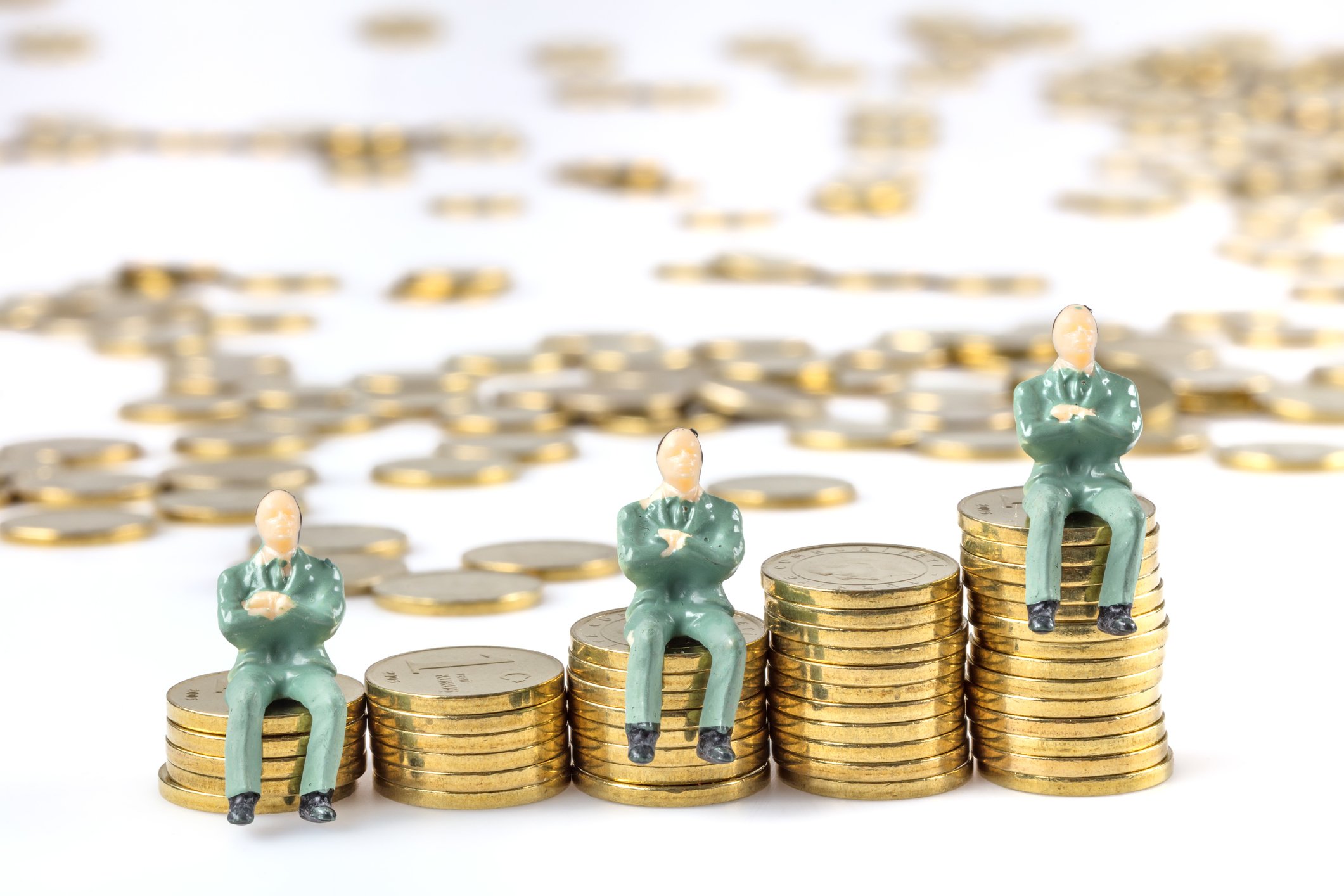 Three figurines sit on several piles of coins.