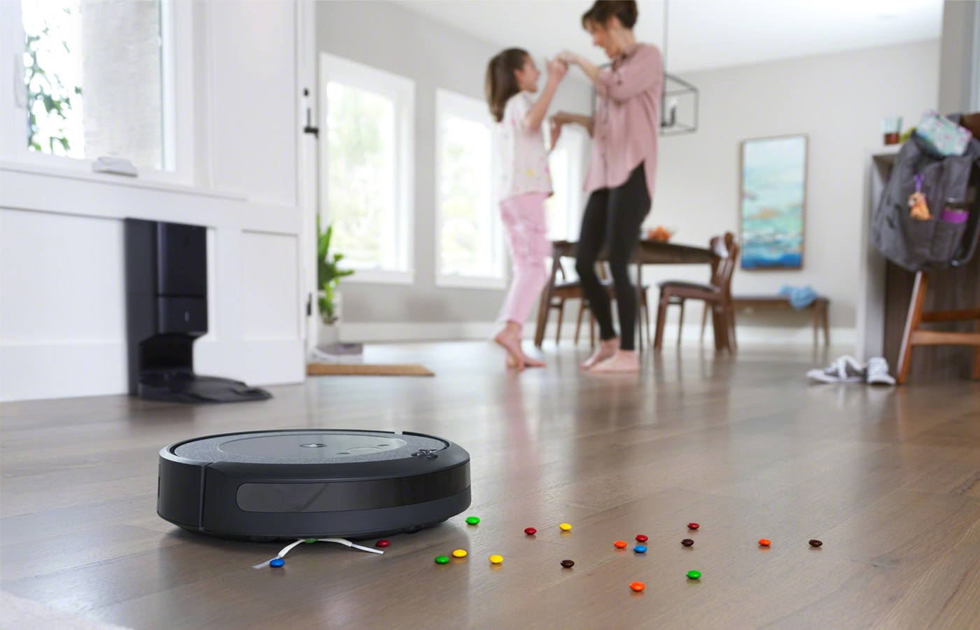 A Roomba cleans up candy as a mother dances with her daughter.