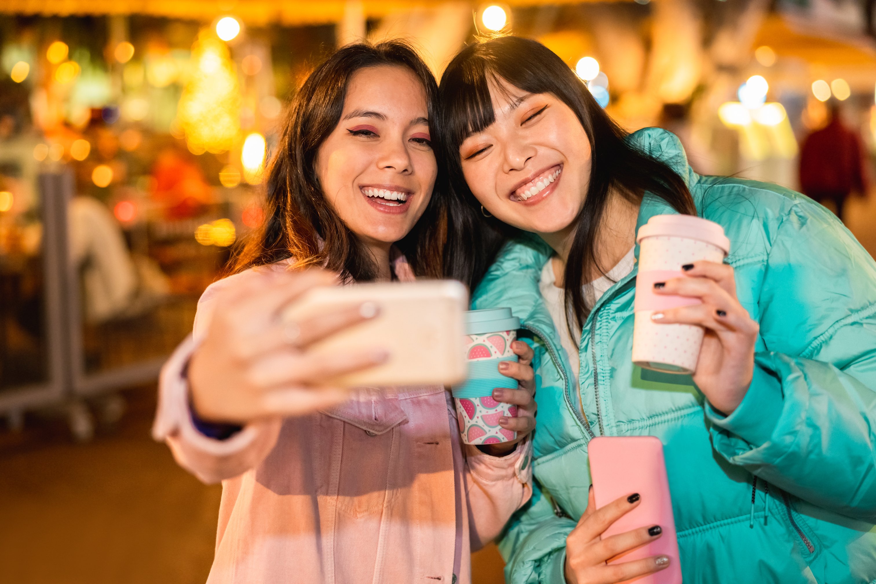 Two young women take a selfie with a smartphone.