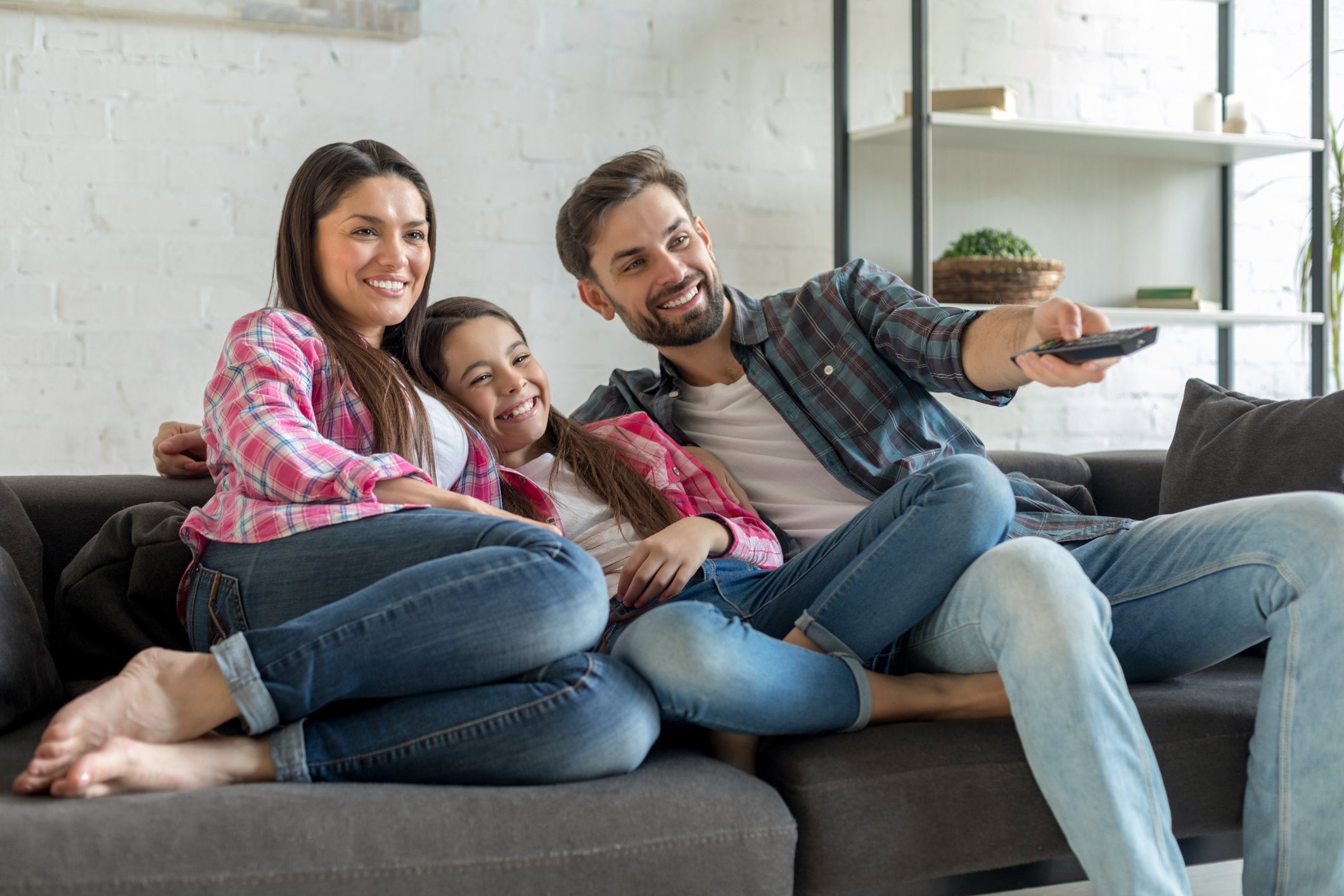 Family sitting on the couch watching TV together
