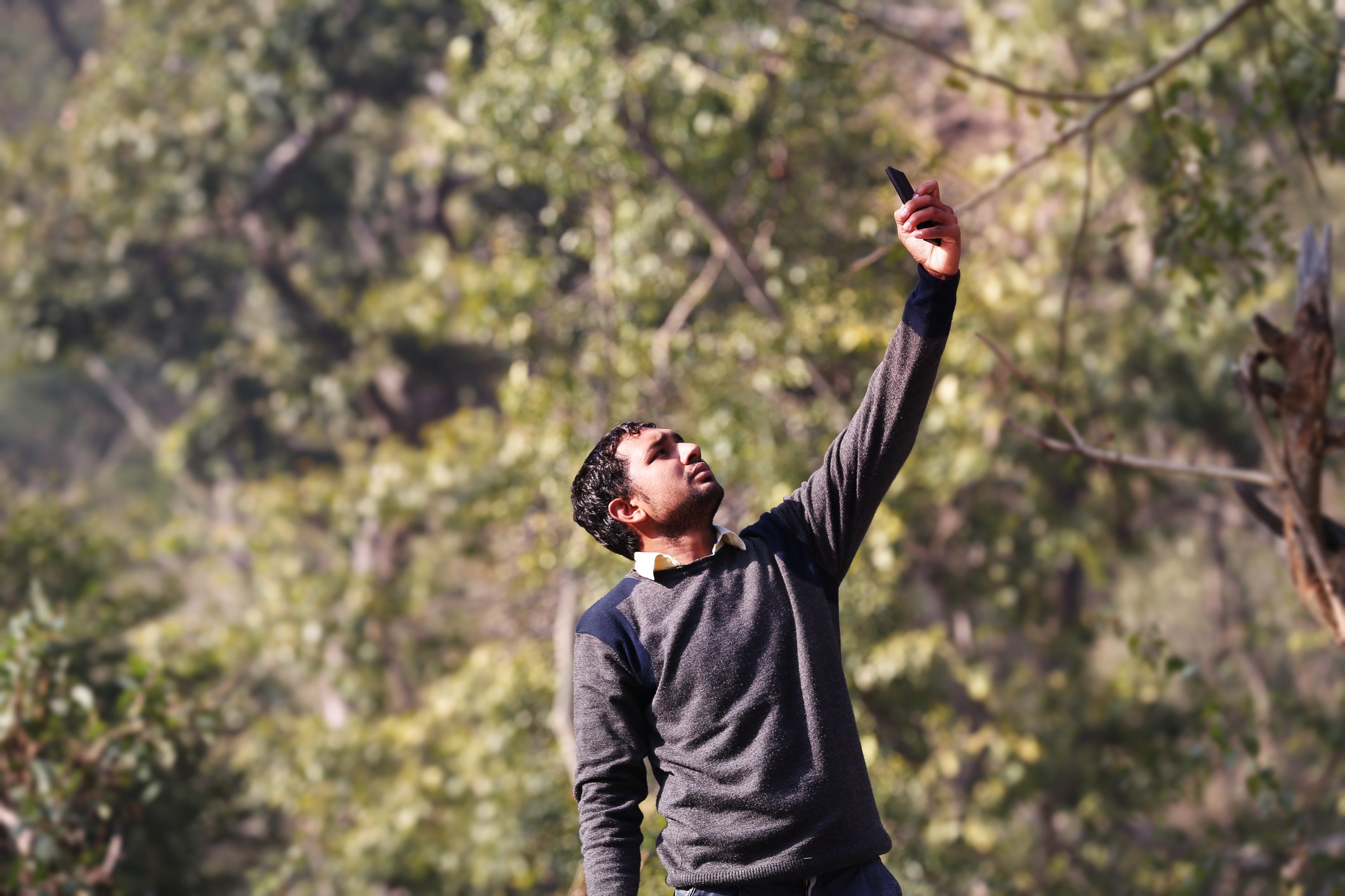 Man in rural area searching for cell phone signal.