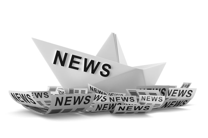 A paper boat that says "news" riding on paper waves.