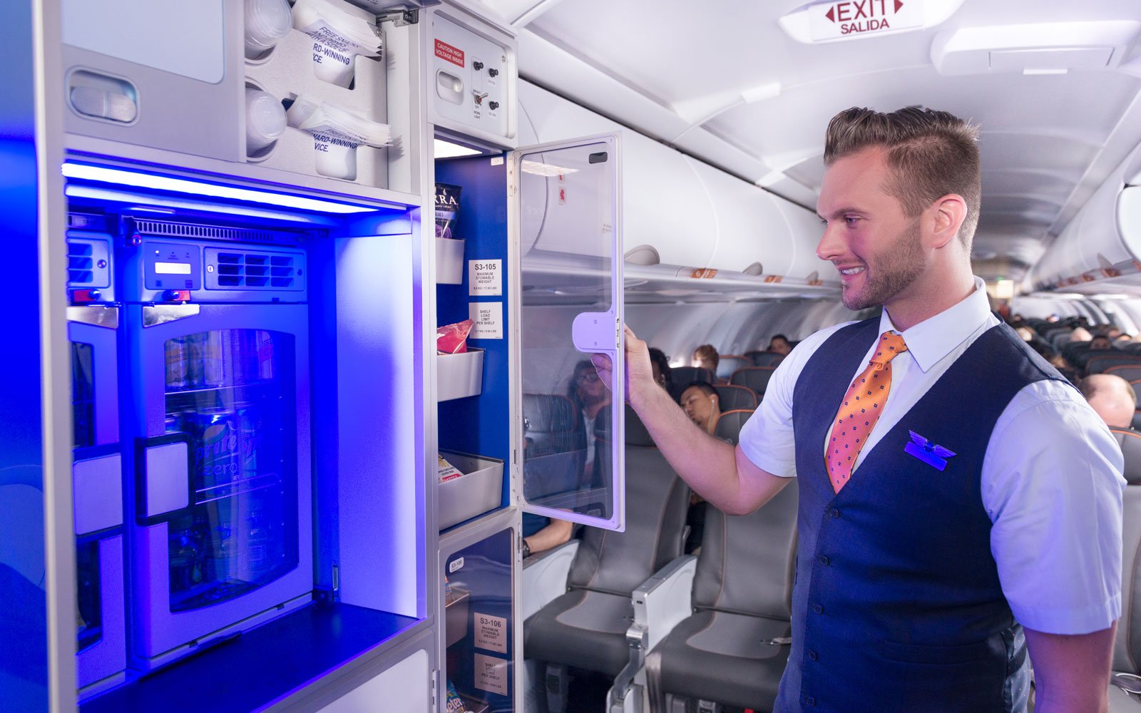 A JetBlue flight attendant checks stations with passengers on a JetBlue plane.