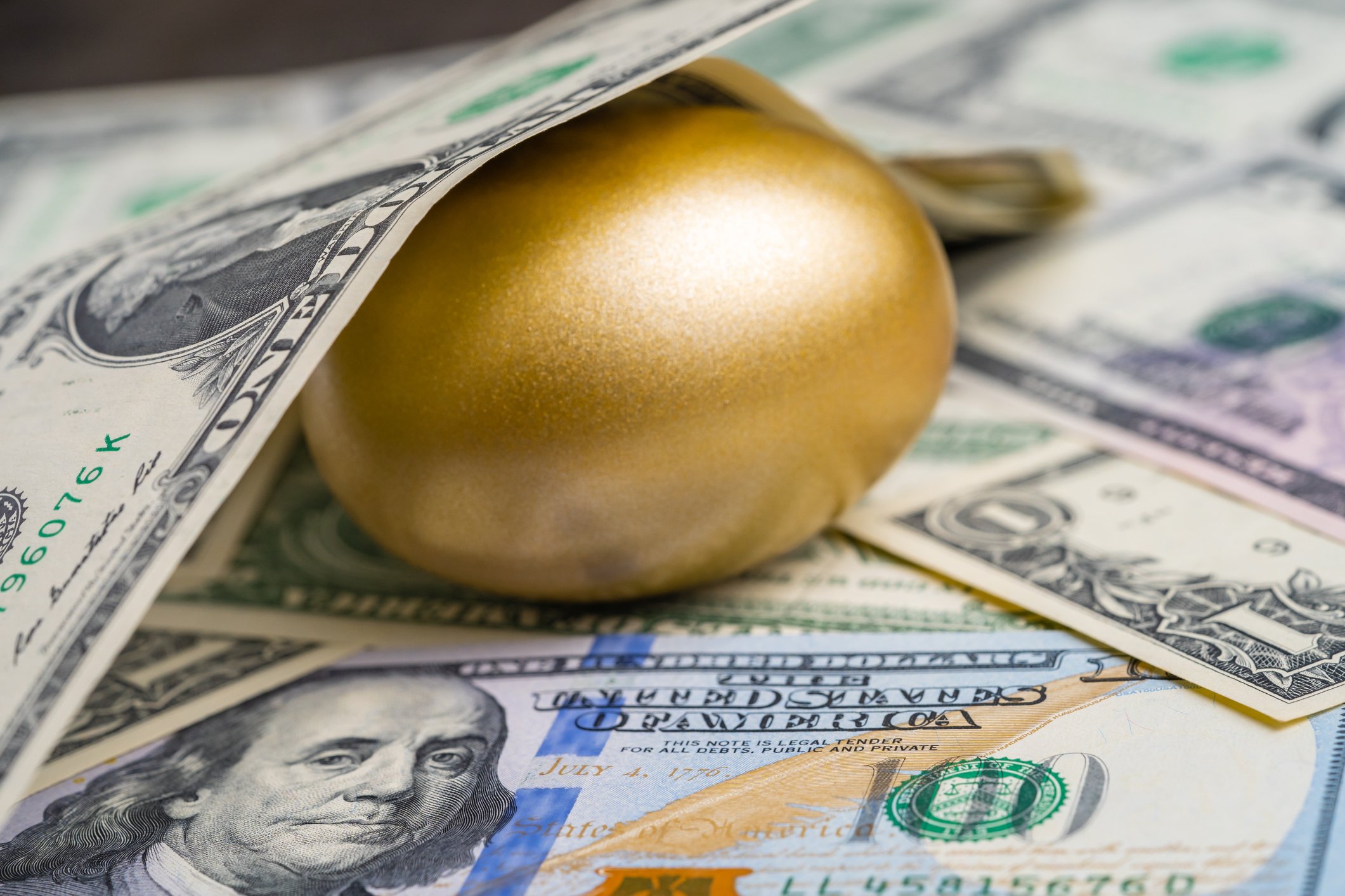 Dollar bills surrounding a golden egg.