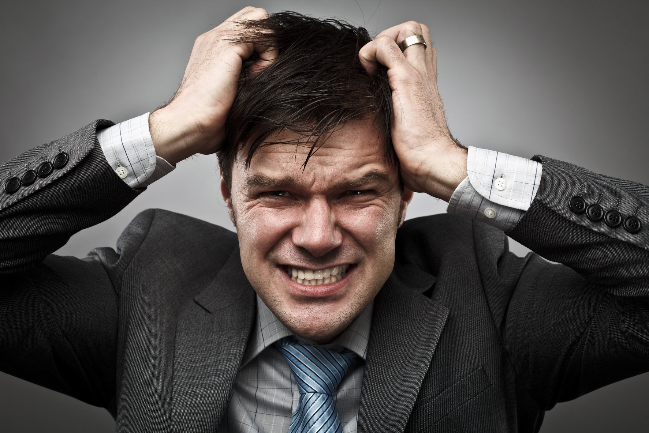 Businessperson clutching their head and wearing a panicked or frustrated facial expression. 