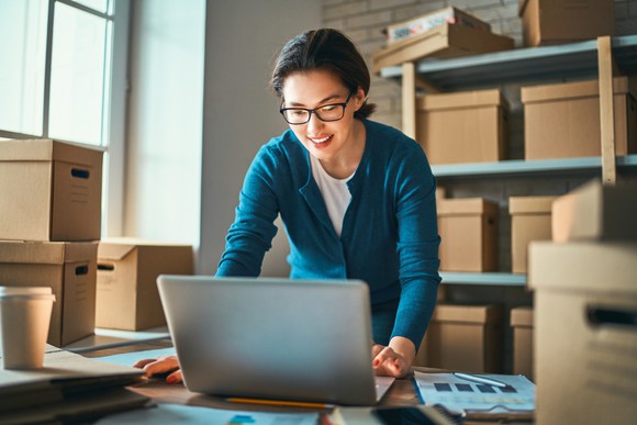 Worker surrounded by boxes using her laptop.