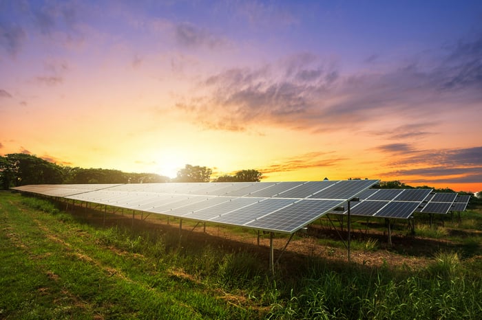 Solar farm with a setting sun in the background. 