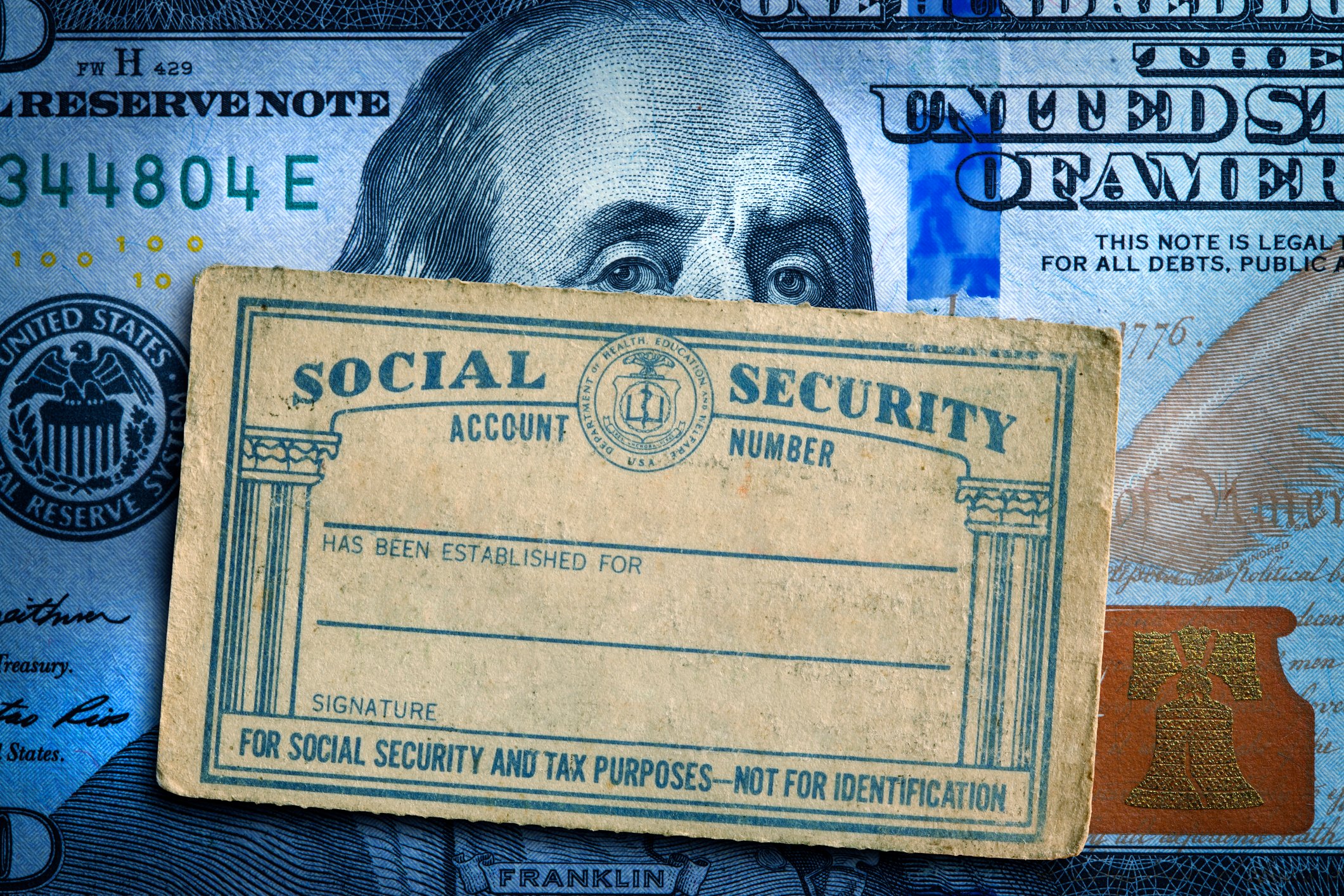 Old social security card in front of money.