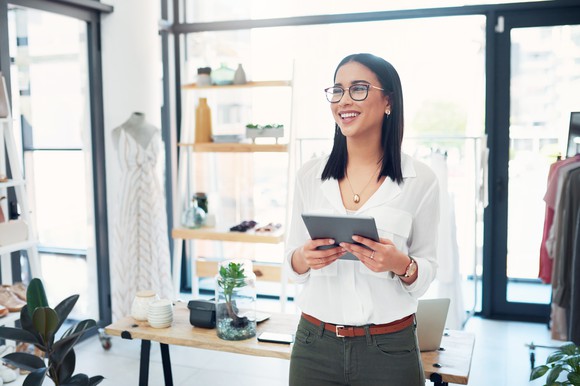 A person in a clothing store holding a tablet.