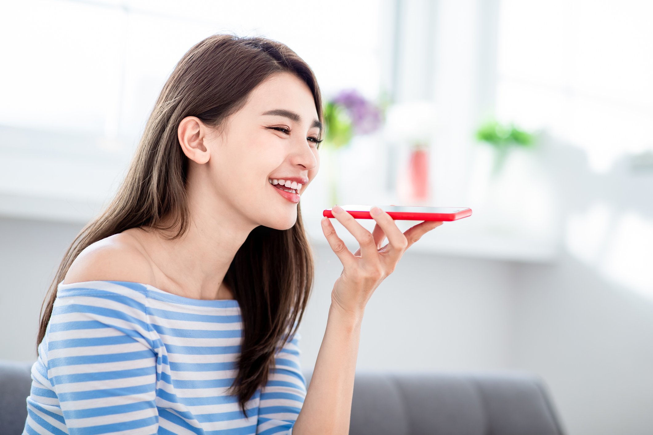 A woman speaks into her smartphone.