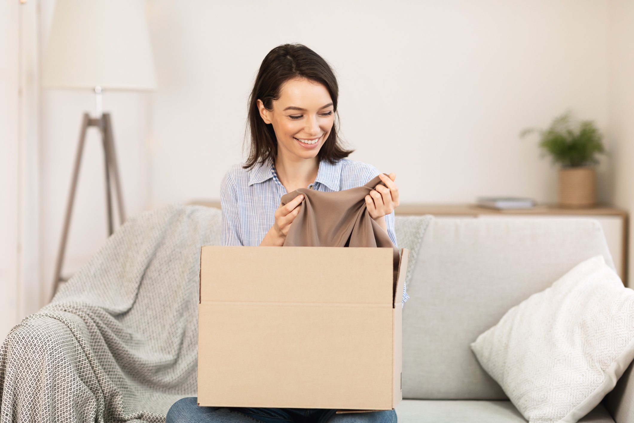 A woman opening a box of clothing.