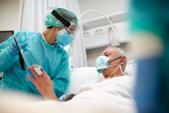 Older man in a hospital bed with a healthcare professional standing next to him