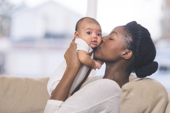 mother holds newborn baby in the living room.